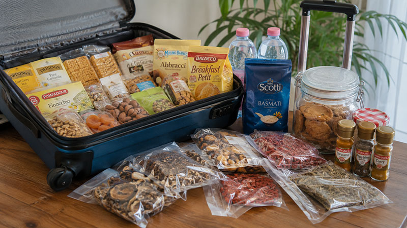 Prodotti alimentari confezionati per un viaggio in Australia con snack, tè, spezie e biscotti ben ordinati